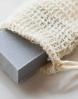 Close-up of a gray soap bar tucked inside a woven agave fiber soap bag