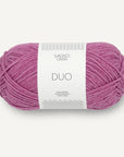 A skein of magenta Sandnes Garn Duo yarn with a label in the center displaying the brand and product name.