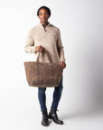 Person holding a brown tote bag against a white background