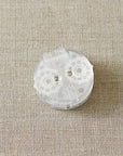 A translucent, matte-finish knitting row counter with magnified numbers, displayed on a textured fabric surface.