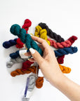 Hand holding a skein of multicolored yarn against a white background