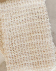 Close-up of stacked woven agave soap saver bags on a marble surface