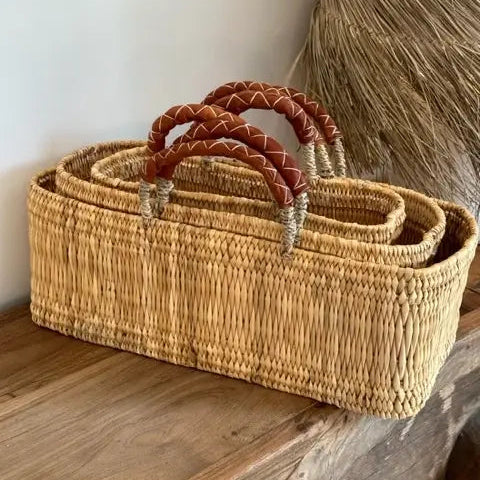 Set of woven baskets with handles on a wooden surface