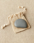 Stone colored Cocoknits tape measure on a beige drawstring bag against a beige fabric background