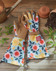 Gardening gloves with floral patterns on a wooden surface with plants and pots.