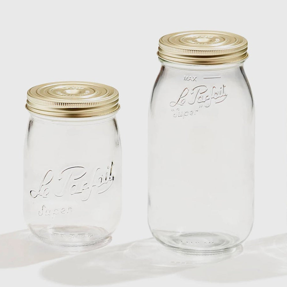 Two clear glass jars with gold lids on a white background