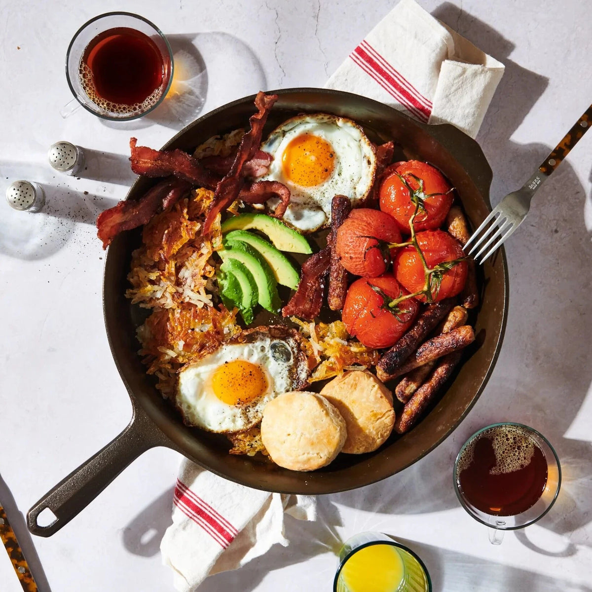 Breakfast hash with eggs, bacon, avocado, and biscuits in a Field cast iron skillet