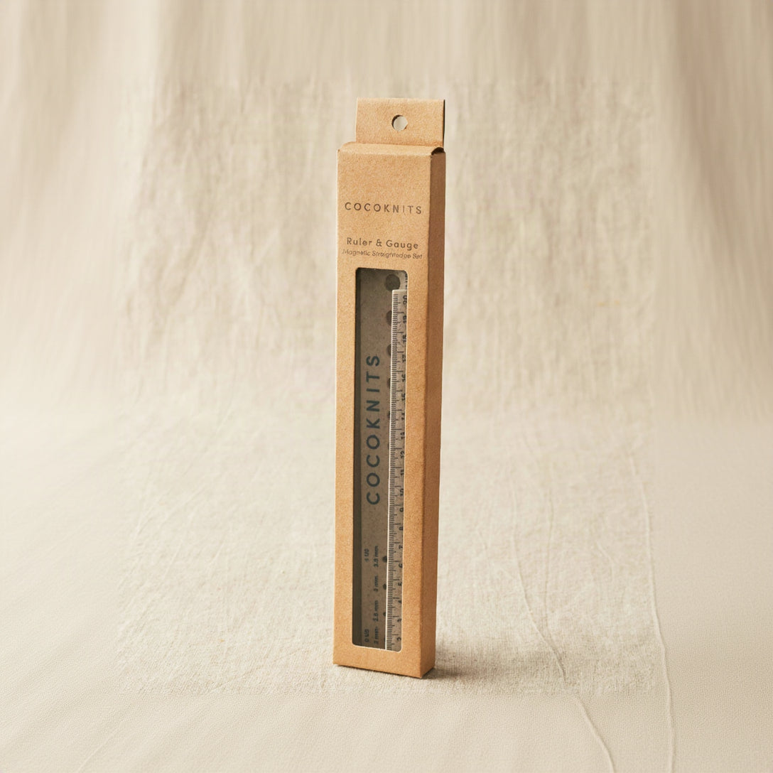 Cocoknits ruler and gauge set in a cardboard box on a beige background