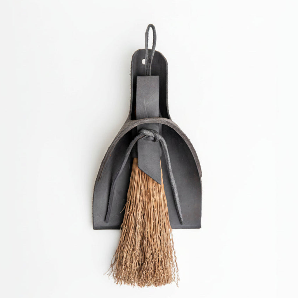 Black leather broom and dustpan set on a white background