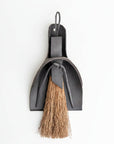 Black leather broom and dustpan set on a white background