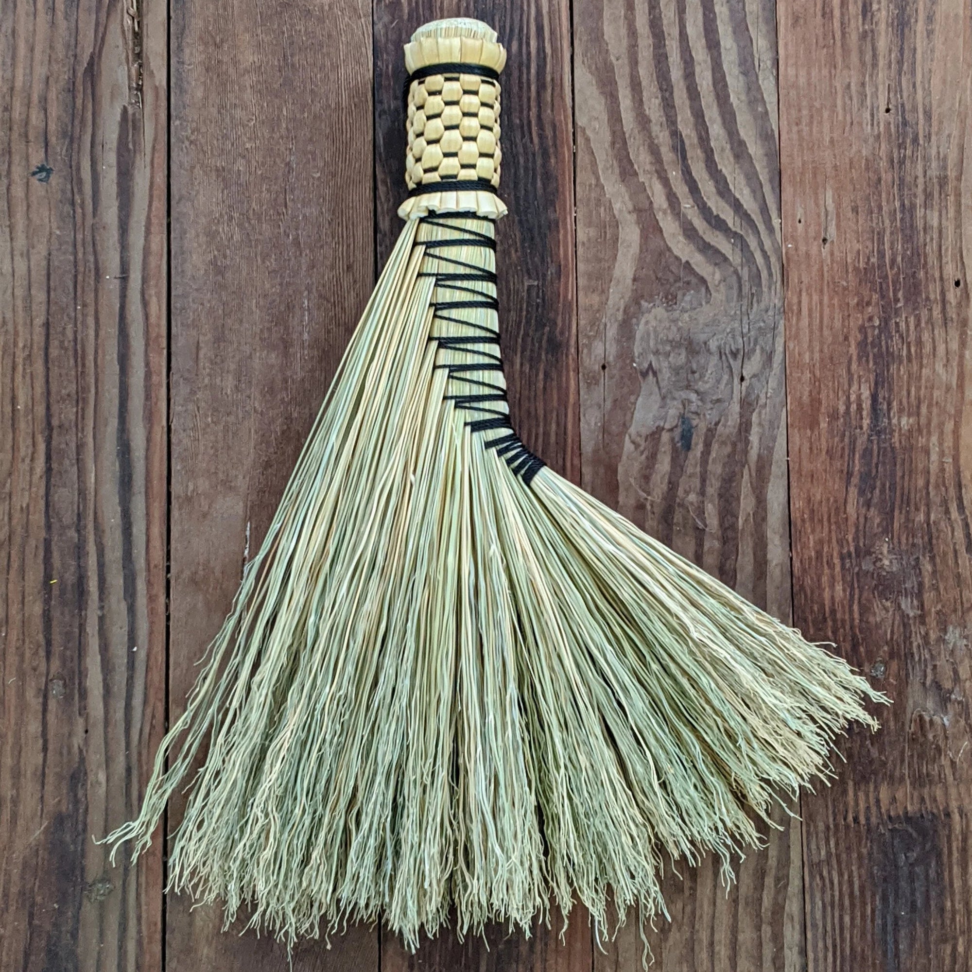 Broom with a woven handle on a wooden background